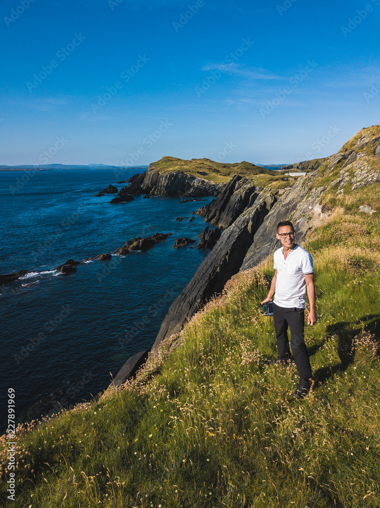 A man on the edge of the cliff of Inishmore Island holds a drone console in his hand A man on the edge of the cliff of Inishmore Island holds a drone console in his hand