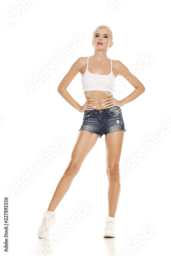 young pretty blonde woman posing in short jeans on white background