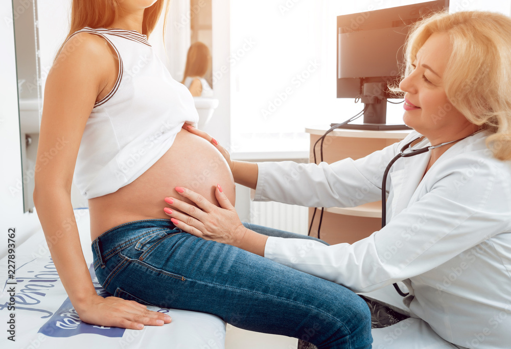 Obraz premium A gynecologist examines a pregnant woman. Patient at doctor office. Pregnant woman at hospital.