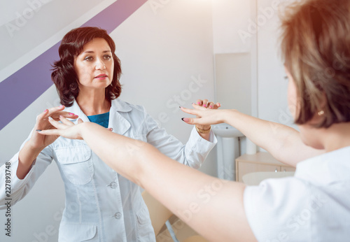 Neurological examination. The neurologist testing reflexes on a female patient using a hammer.