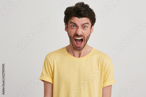 Foto Young brown hair man with beard looks bawling and yelling, wears yellow classic