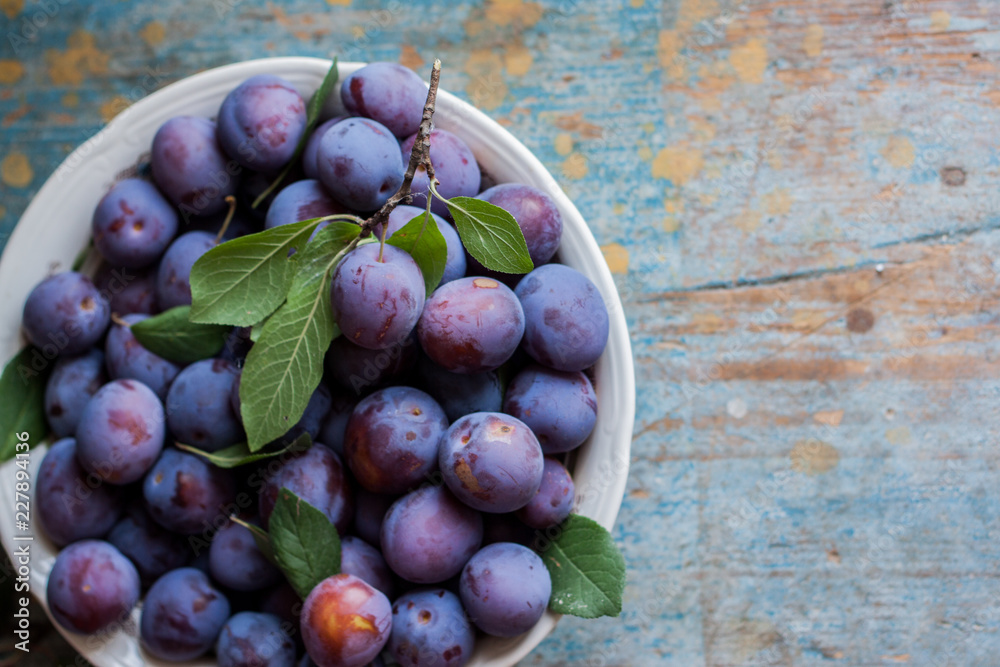 Fototapeta premium Plum plate on wooden background.