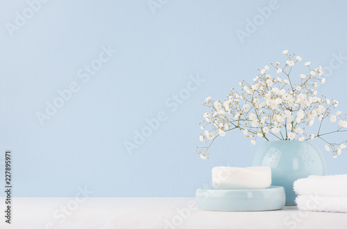 Fototapeta Elegant acessories for dressing table - soft pastel blue ceramic bowls, white flowers, products for skin and body care on white wood board and blue wall