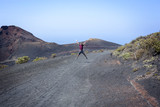 Man jumping with joy among volcanoes with open arms