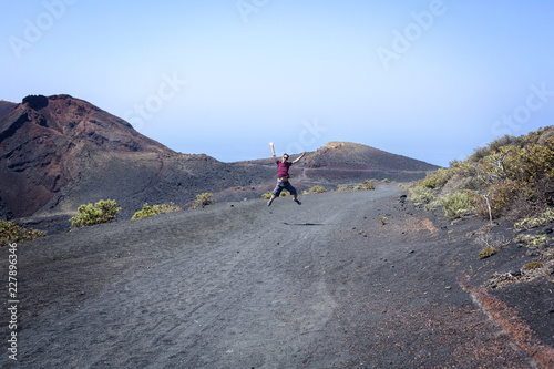 Man jumping with joy among volcanoes with open arms photo