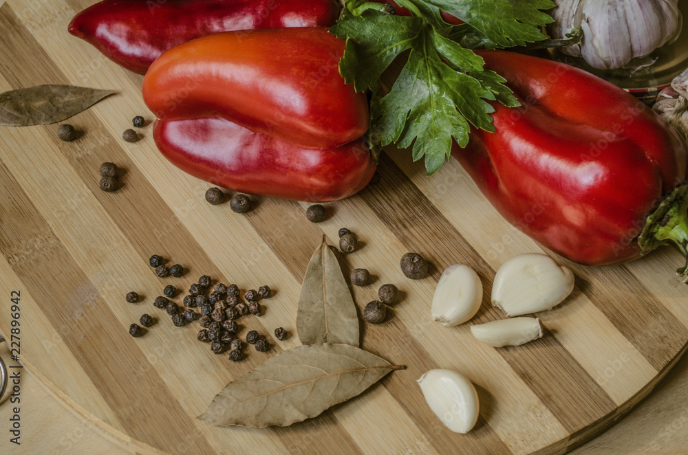 Bell red pepper with celery leaves, bay leaves, garlic and allspice lie on a wooden striped cutting board
Bell red pepper with celery leaves, bay leaves, garlic and allspice lie on a wooden striped cutting board