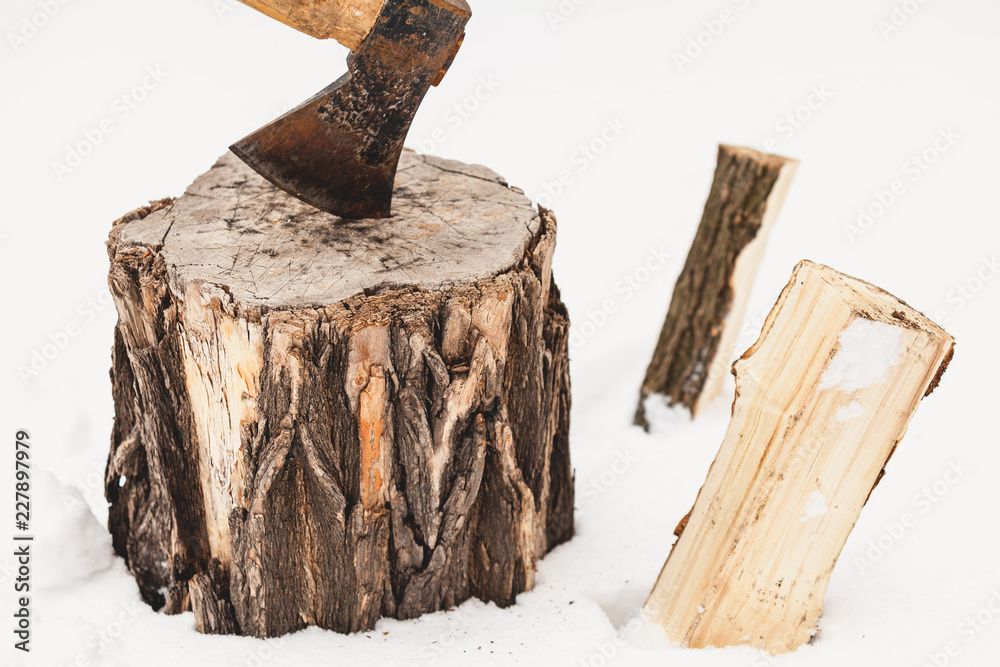 ax sticks out in stump against background of white snow ax sticks out in stump against background of white snow