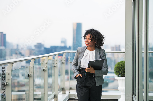 Canvas Print A portrait of a businesswoman with clipboard walking on a terrace