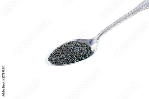 The basil seeds are put in a spoon and placed on a white background.