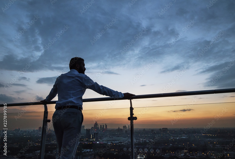 A rear view of businessman standing against London view panorama at dusk. - obrazy, fototapety, plakaty 