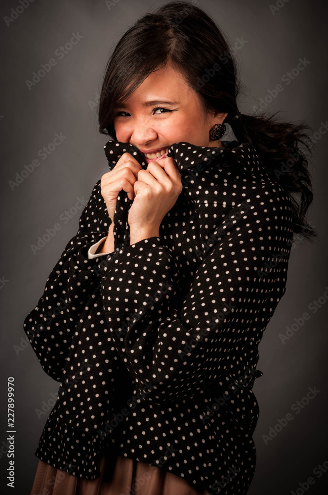 Fashion portrait in studio of beautiful young asian smiling woman feeling happy in casual dress over dark background
