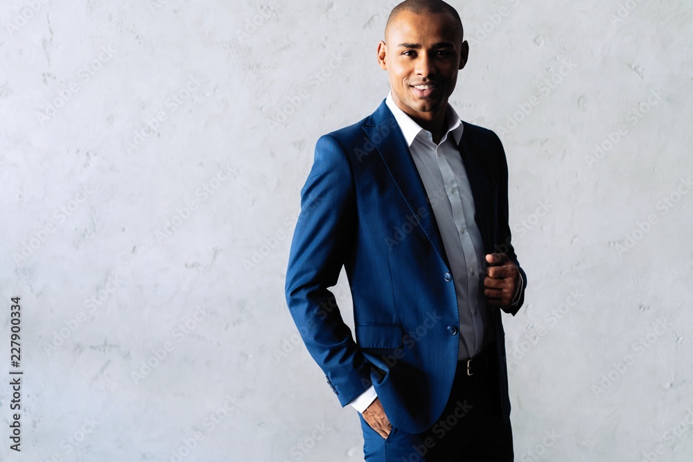 Cool african businessman standing on grey background. Cool african businessman standing on grey background.