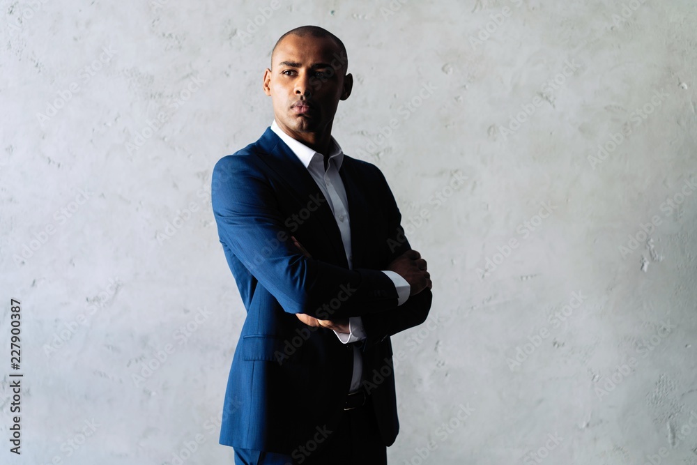 Cool african businessman standing on grey background. Cool african businessman standing on grey background.