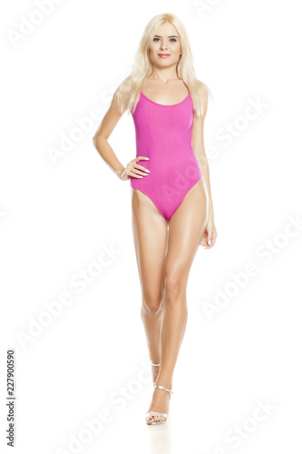 young pretty blonde woman walking in pink sweamsuit on white background
