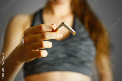 Sporty girl holding a broken cigarette in her hand. Close up. Isolated background
