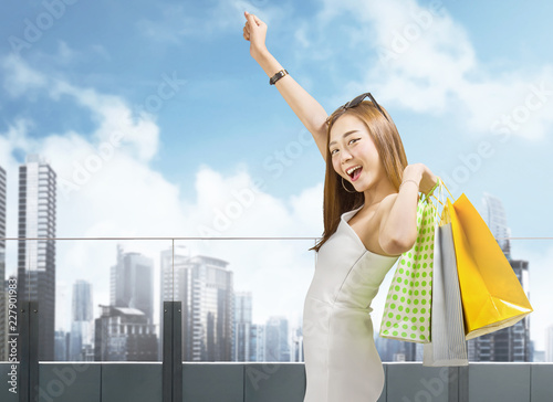 Attractive chinese woman holding colored shopping bags on the city