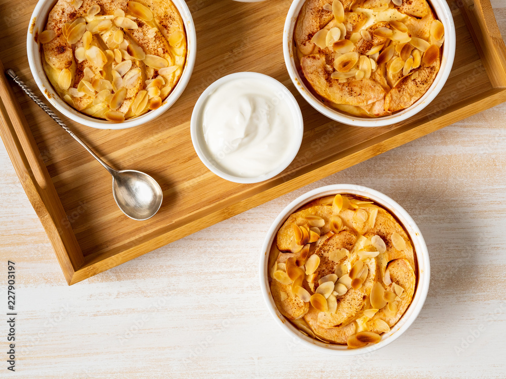 Cheesecake on white wooden table in kitchen. Delicate curd dessert with apples, almond flakes and cinnamon, top view, above Cheesecake on white wooden table in kitchen. Delicate curd dessert with apples, almond flakes and cinnamon, top view, above