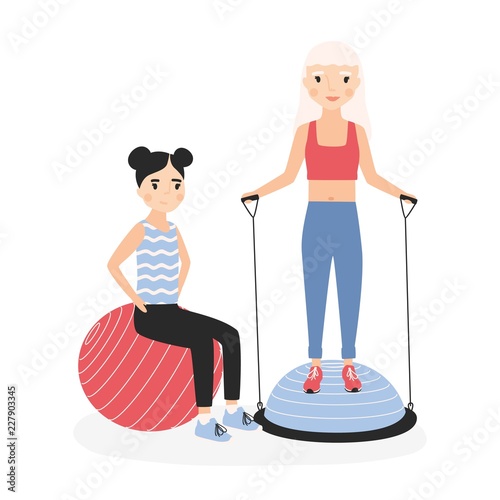 Smiling mother and daughter performing aerobics exercises with gym balls