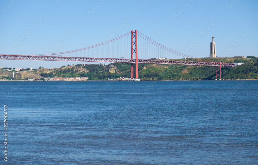 25th of April Bridge suspension bridge over river Tejo with Jesus Christ the King Statue on background in Lisbon. Portugal 25th of April Bridge suspension bridge over river Tejo with Jesus Christ the King Statue on background in Lisbon. Portugal