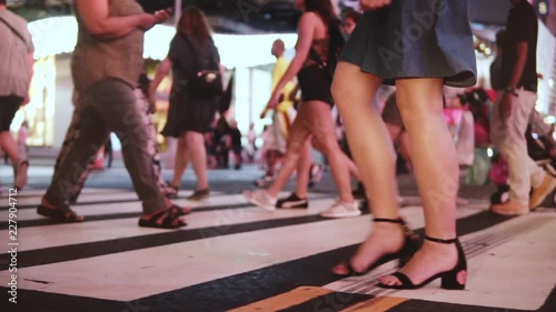 Slow motion lifestyle shot of young female fashion blogger crossing a crowded street at night in Times Square, New York.