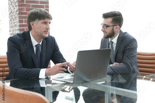Two businessmen discussing tasks sitting at office table. © ASDF