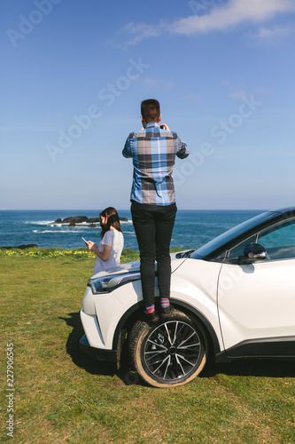 Young couple traveling by car making a stop to photograph the landscape