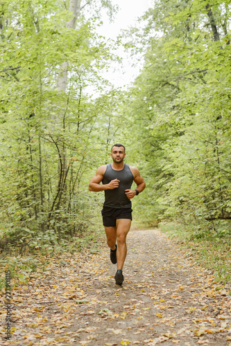 Jogging in the forest. Athlete running through the woods.