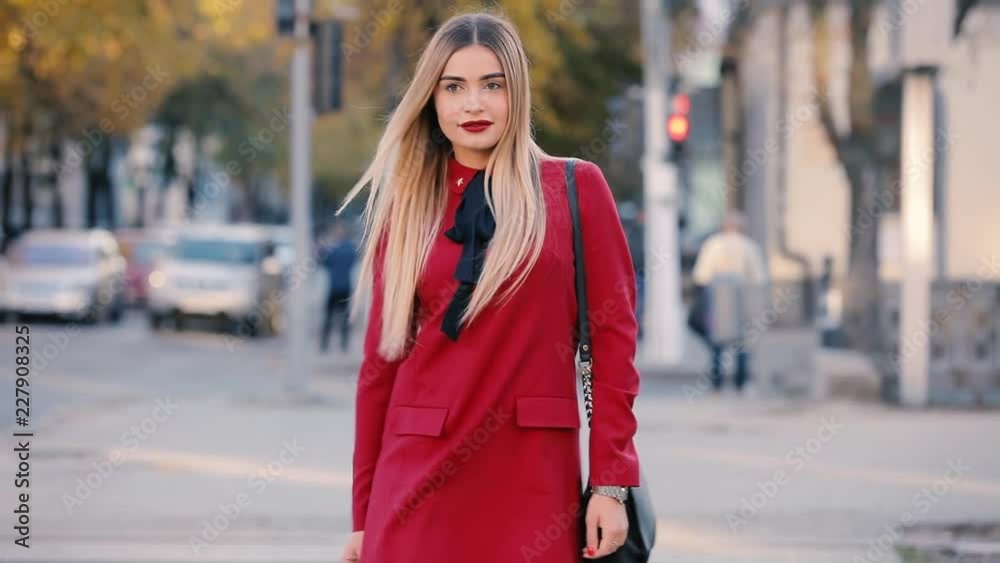 Lady in red dress walking along city street Lady in red dress walking along city street