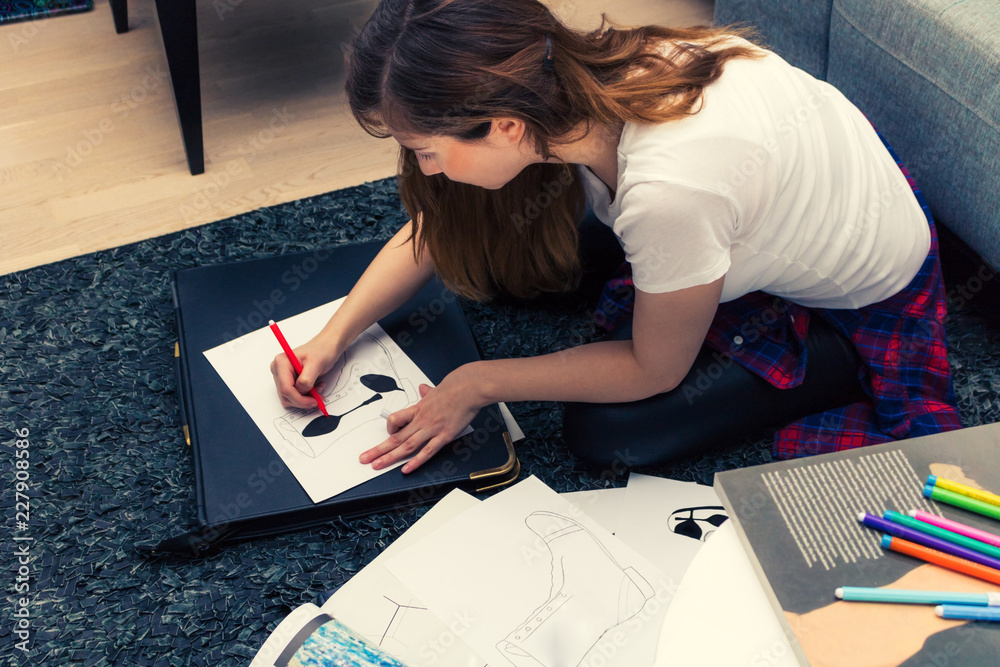 Young creative woman sketching on the paper in a studio. Young creative woman sketching on the paper in a studio.