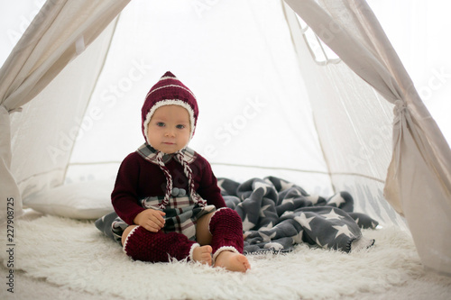 Stylish little toddler boy, playing around christmas decoration © Tomsickova