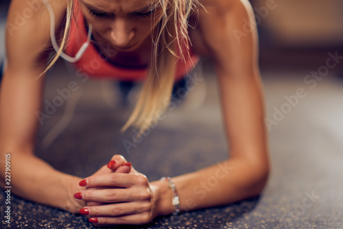 Close up of woman doing planks on a gym floor.