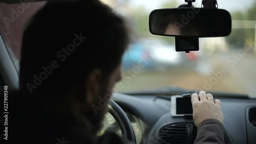 Wallpaper Mural A man gets into the car and turns on the navigator on the smartphone, soft focus Torontodigital.ca