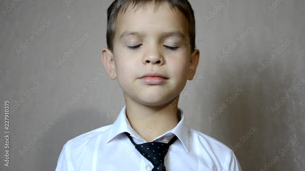 Young businessman the boy is wearing a white shirt and tie. schoolboy. Concept of personal growth or learning. Button buttons. straightens tie. Fashion portrait of little handsome boy in office Young businessman the boy is wearing a white shirt and tie. schoolboy. Concept of personal growth or learning. Button buttons. straightens tie. Fashion portrait of little handsome boy in office