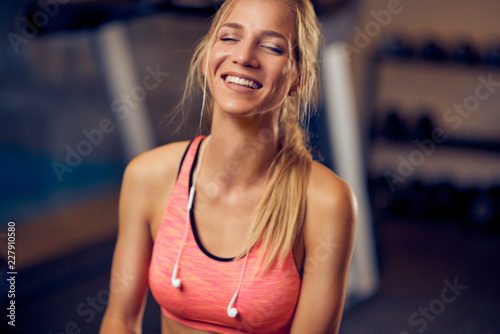 Close up of smiling girl in a gym .Headphones around neck.