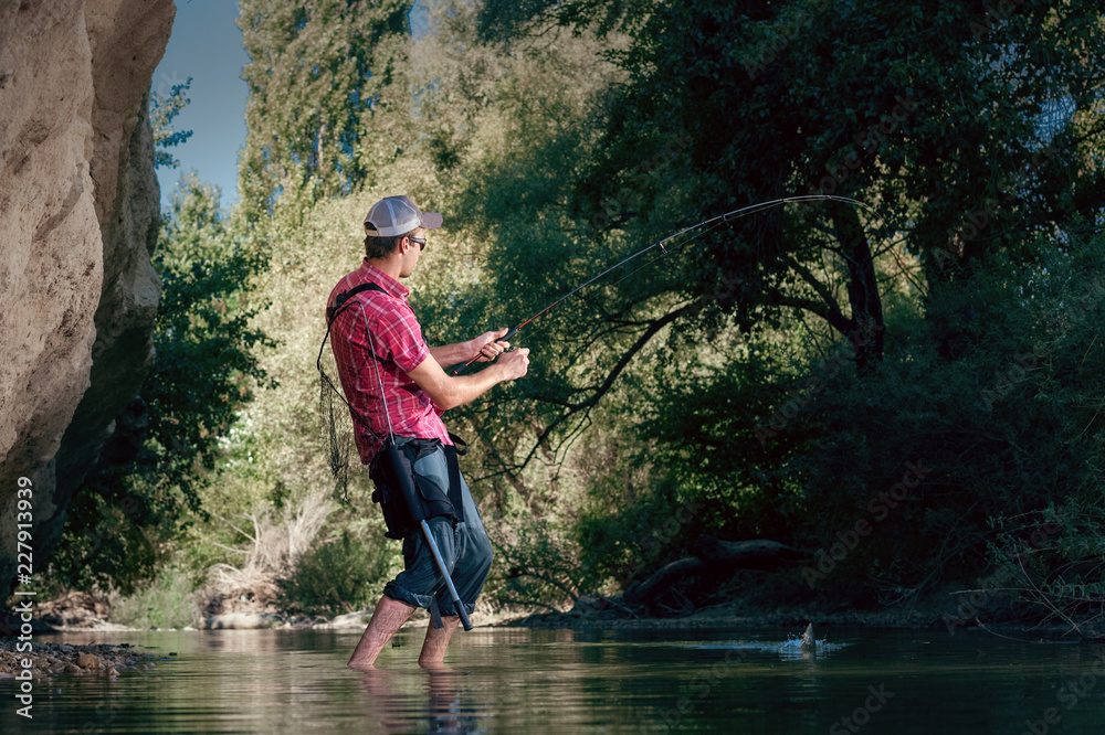 Fishing on the river. Man catches a fish on a lure Spinning. Fisherman with a fishing rod.