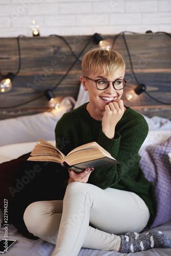 Young woman reading a book in bedroom