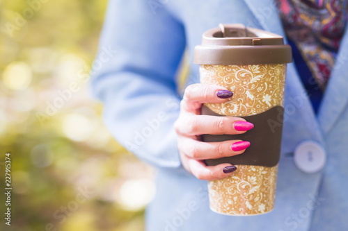 Fototapeta Naklejka Na Ścianę i Meble -  Autumn, drinks and people concept - Cup of hot drink in woman's hand