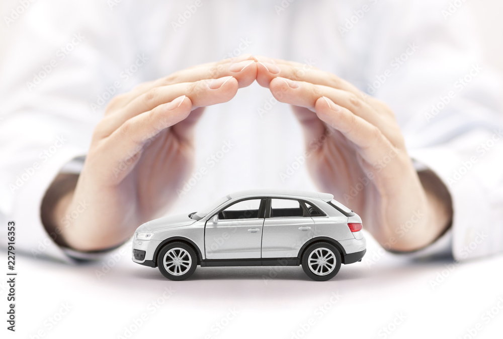 Obraz premium Ubezpieczenie samochodu. Mały srebrny samochód pokryty rękami.