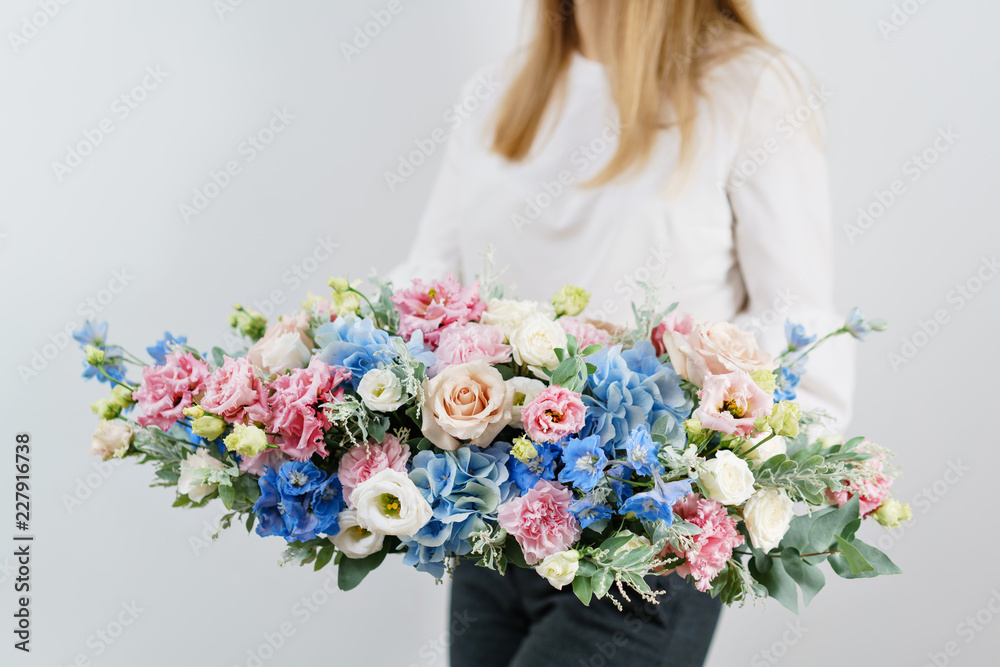beautiful spring bouquet. Young girl holding a flowers arrangement with various of colors. white wall.