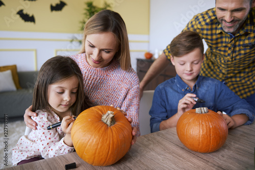 Children and parents drawing on pumpkins photo