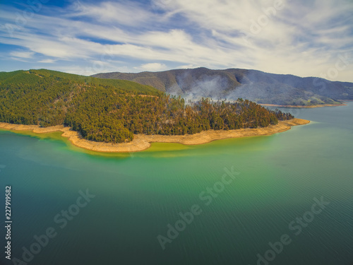 Aerial view of forest fire on shores of Blowering reservoir lake