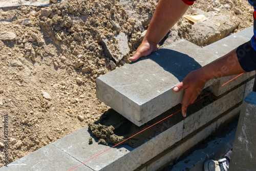 worker make concrete wall by cement block and plaster at construction site