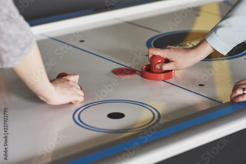 Hands of young people holding striker on air hockey table in game room photo