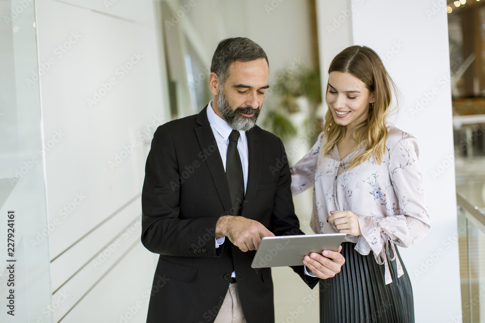 Young businesswoman and businessman look on digital tablet and discuss aout project Young businesswoman and businessman look on digital tablet and discuss aout project