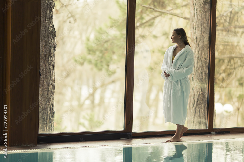 Pretty young woman standing by swimming pool Pretty young woman standing by swimming pool