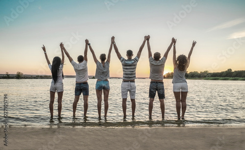 Silhouette of group young people on the beach under sunset sky 