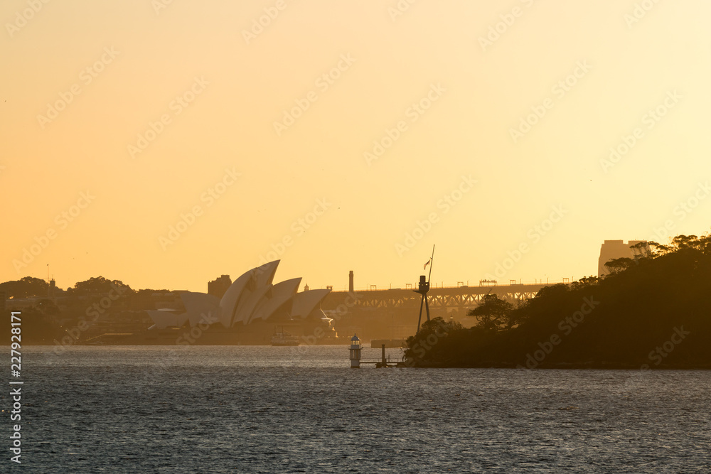 Orange glowing sunset over Sydney Harbour and it's famous tourist attraction. Sydney, New South Wales, Australia.