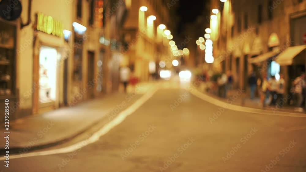 Out of focus background plate of urban European street at night with people