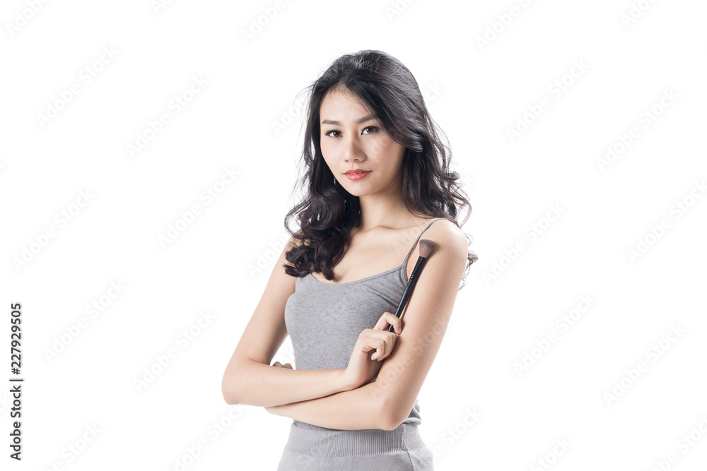 Cheerful young woman wearing light dress standing and posing on isolates white background.Lady flicking holding make up brush. Cheerful young woman wearing light dress standing and posing on isolates white background.Lady flicking holding make up brush.