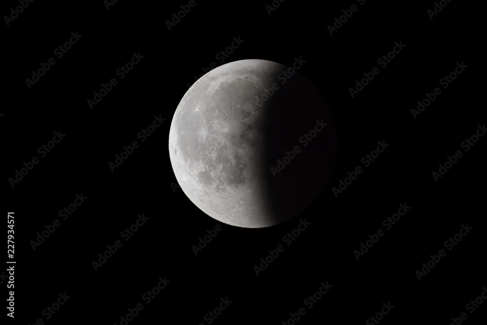 Super Bloody Moon, full eclipse end phase against black sky background, half of the Moon surface covered by Earth's shadow Super Bloody Moon, full eclipse end phase against black sky background, half of the Moon surface covered by Earth's shadow